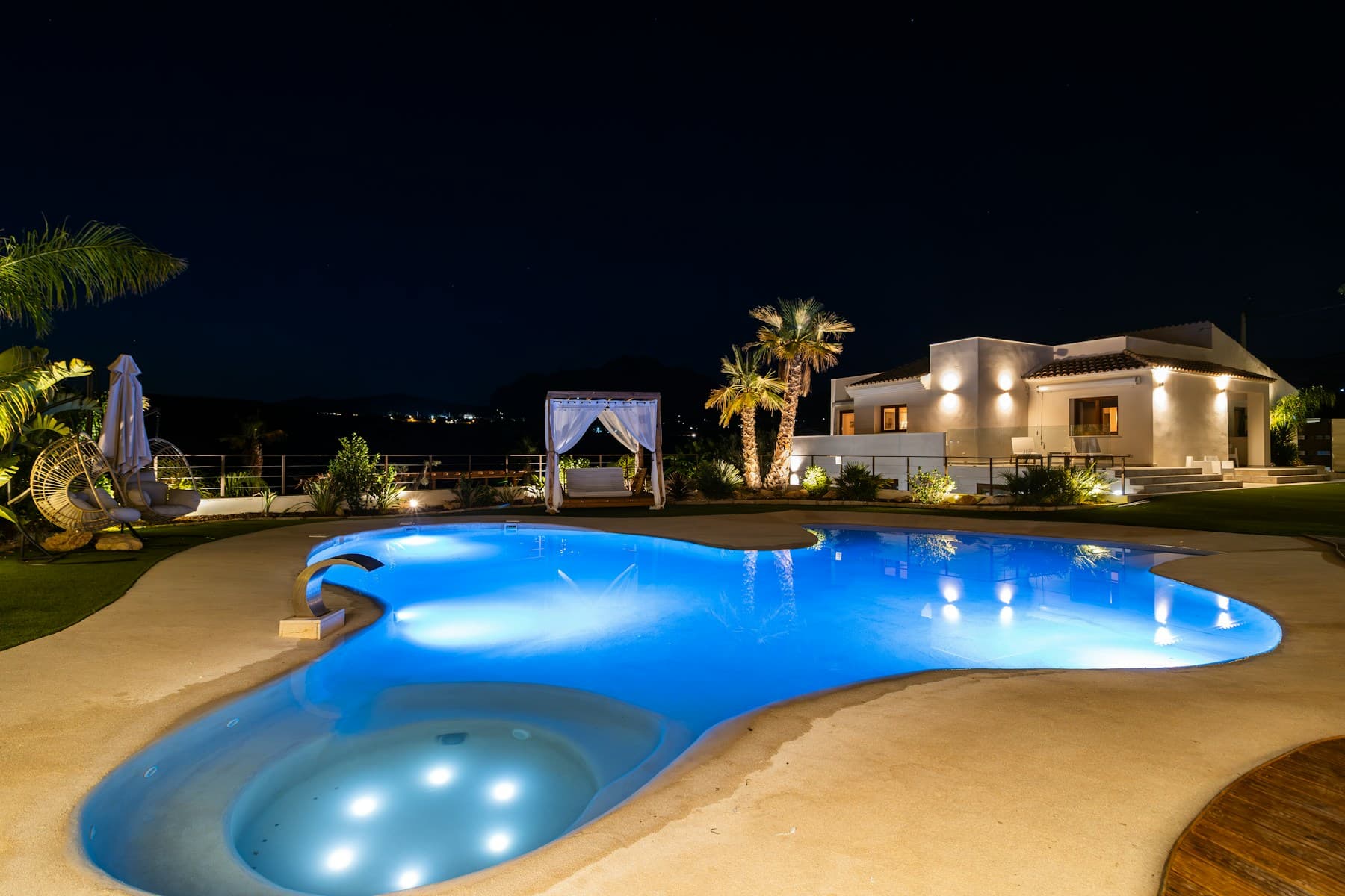 Luxury private villa with an illuminated swimming pool at night